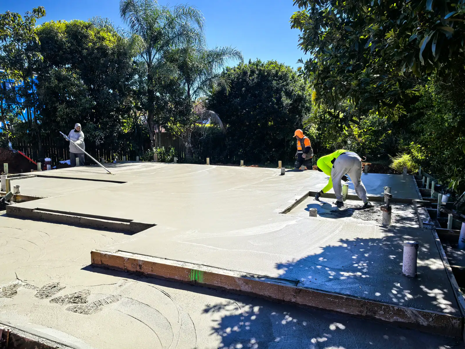 Workers screeding and finishing the freshly poured concrete slab — 11 August 2026 · Slab · Concrete slab completed